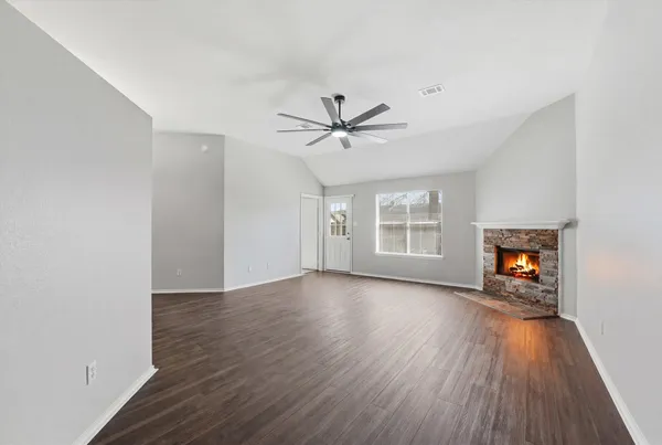 an empty room with wooden floor a ceiling fan and windows