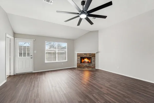 an empty room with wooden floor chandelier fan and windows