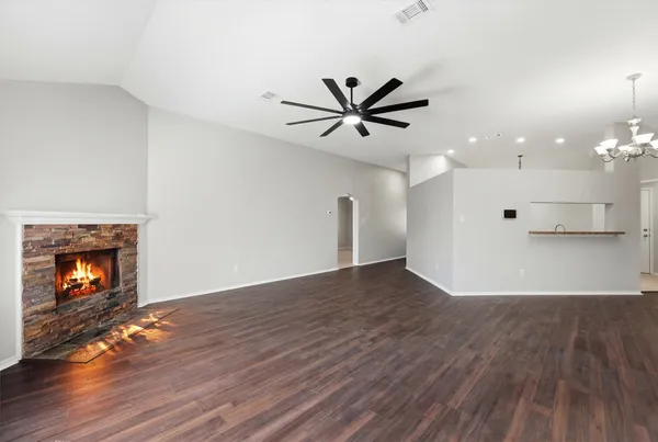 a view of an empty room with wooden floor and a fireplace