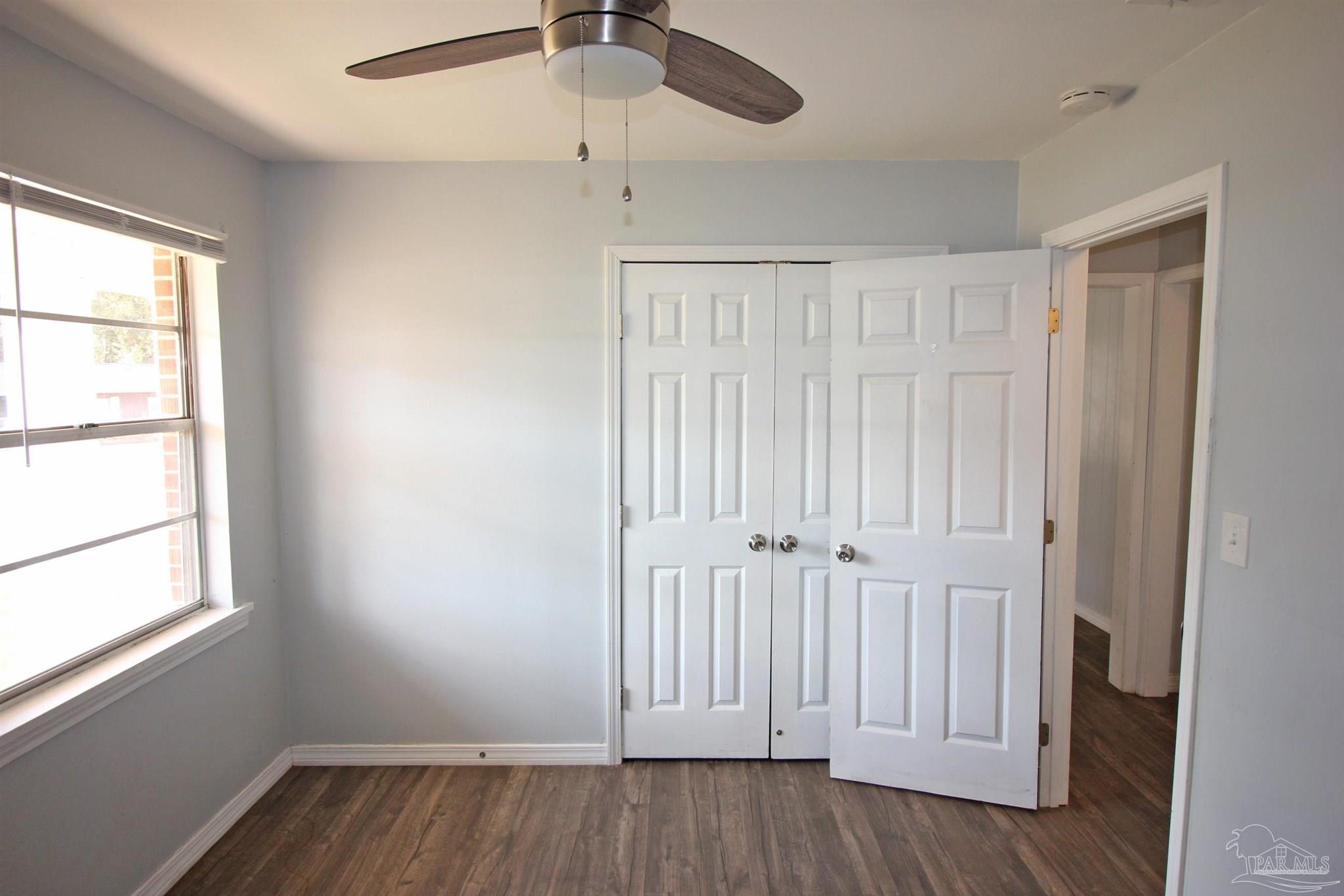 141 Holt Street Flomaton, AL 36441 - Photo 21 of 28 an empty room with wooden floor fan and windows