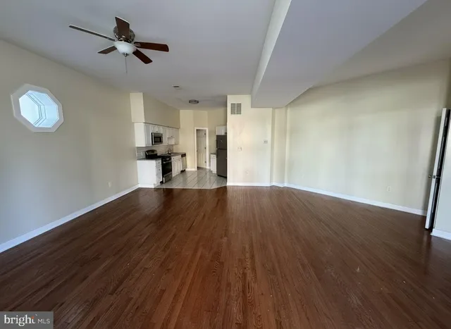 a view of empty room with wooden floor and ceiling fan