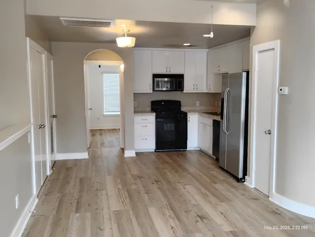 a view of kitchen with kitchen island wooden floor and refrigerator