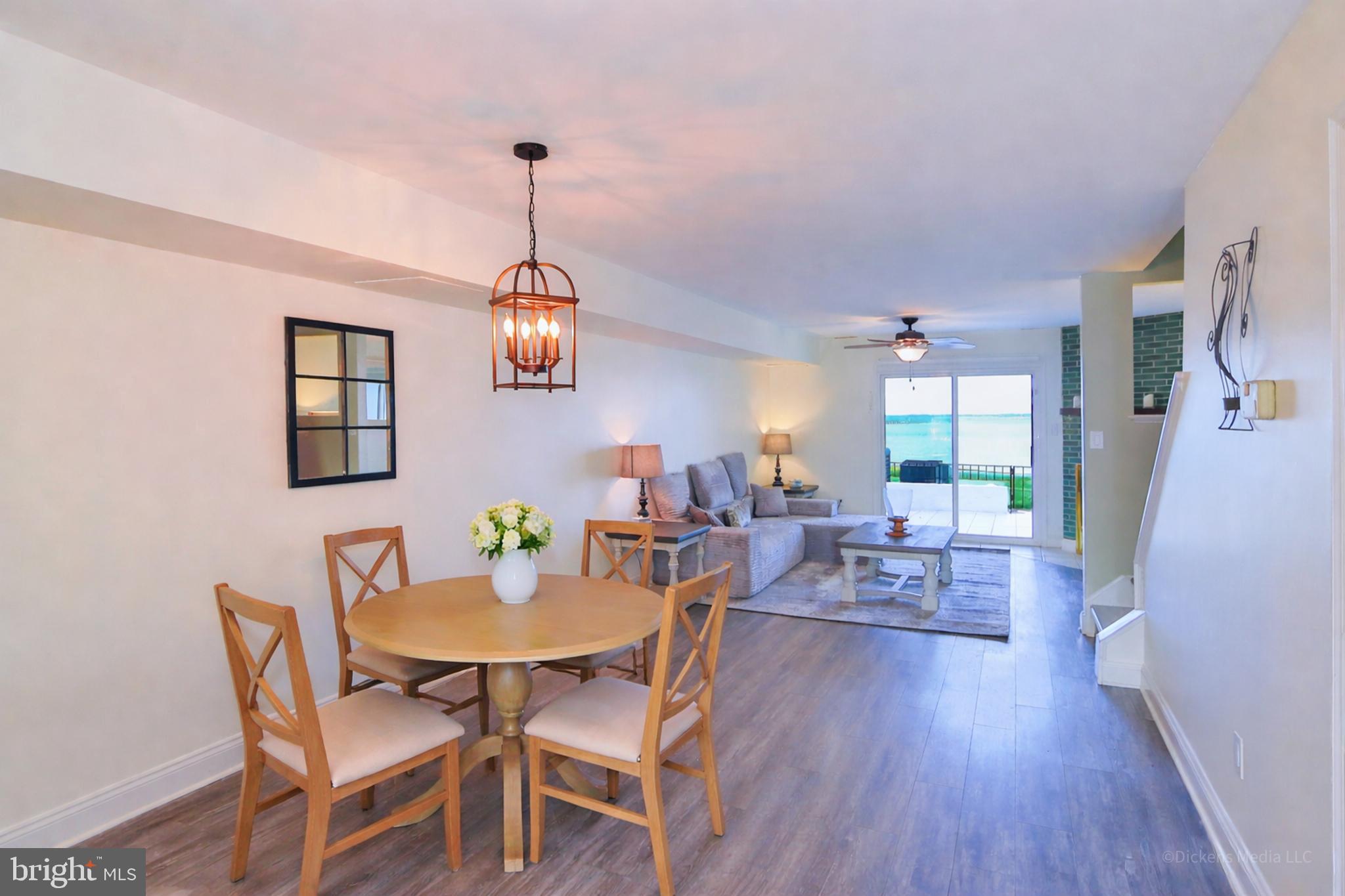 15 Queen Anne Way, Unit E Chester, MD 21619 - Photo 8 of 18 a dining room with wooden floor a chandelier a wooden table and chairs