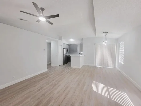 a view of a livingroom with a ceiling fan wooden floor and a ceiling fan