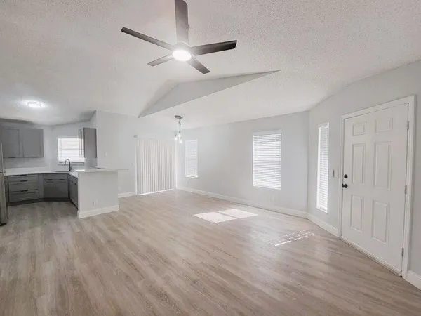 a view of an empty room with a window and a kitchen