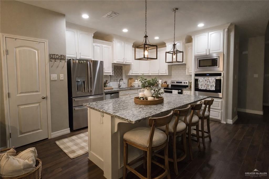 4894 County Road, Unit 2015 Odem, TX 78370 - Photo 6 of 20 Kitchen with stainless steel appliances, white cabinetry, a breakfast bar, a center island, and dark wood-style floors