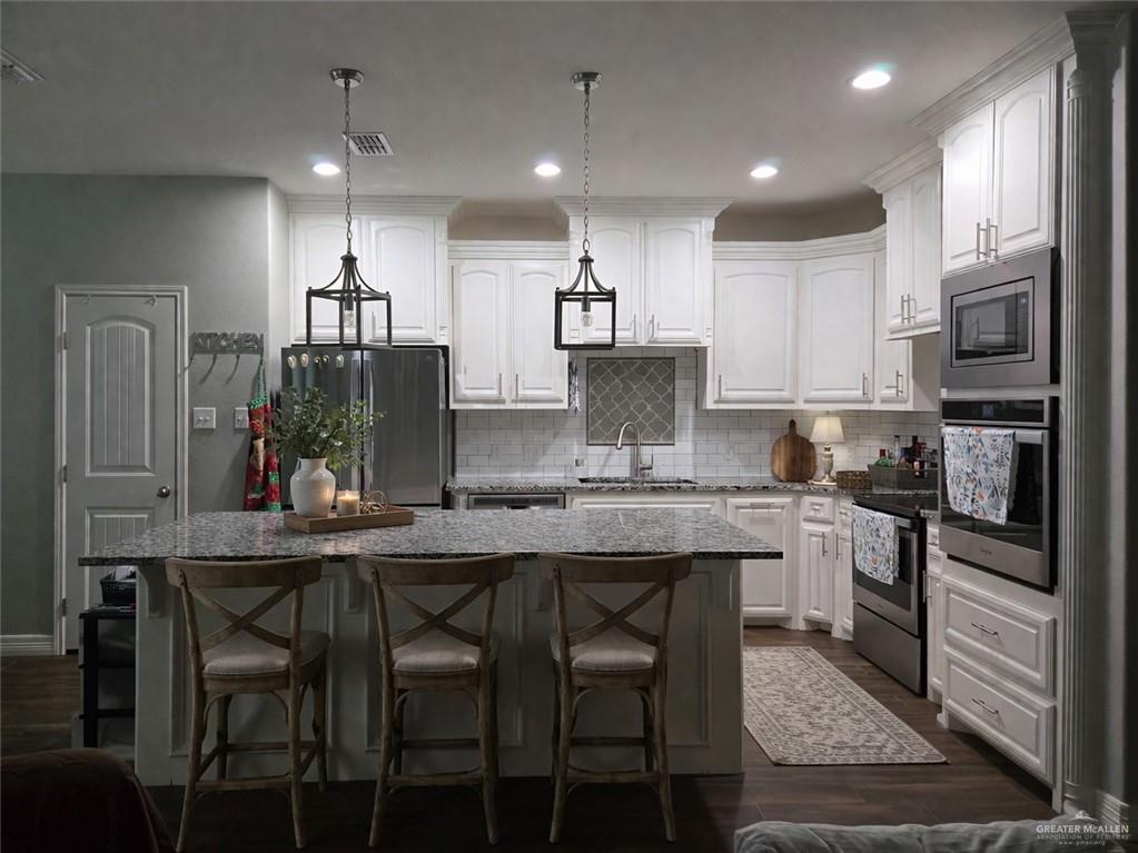 4894 County Road, Unit 2015 Odem, TX 78370 - Photo 7 of 20 Kitchen with a kitchen breakfast bar, a kitchen island, stainless steel appliances, dark stone countertops, and dark wood-style flooring