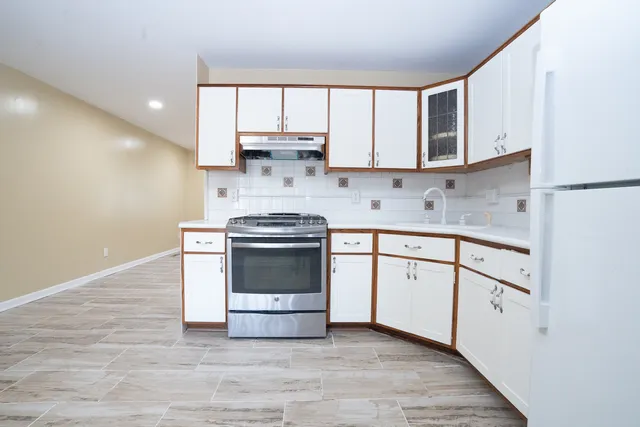 a kitchen with stainless steel appliances granite countertop a stove a sink and white cabinets