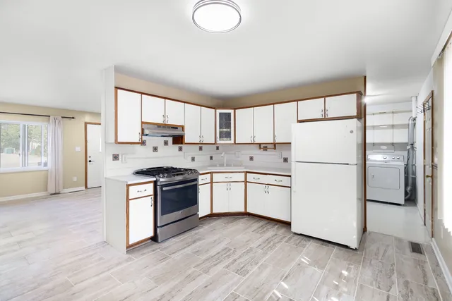 a kitchen with a refrigerator a stove top oven a sink and a window