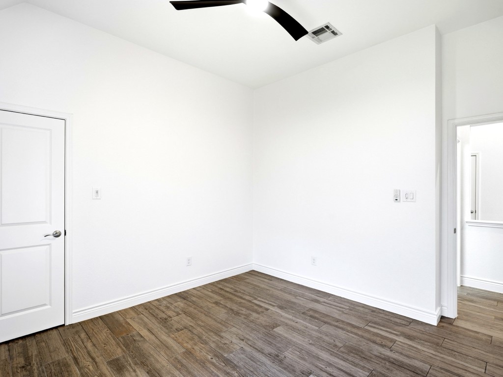 109 Lake Spring Circle Georgetown, TX 78633 - Photo 24 of 38 Wood-look tile flooring and a contemporary ceiling fan add style to this bright primary bedroom.