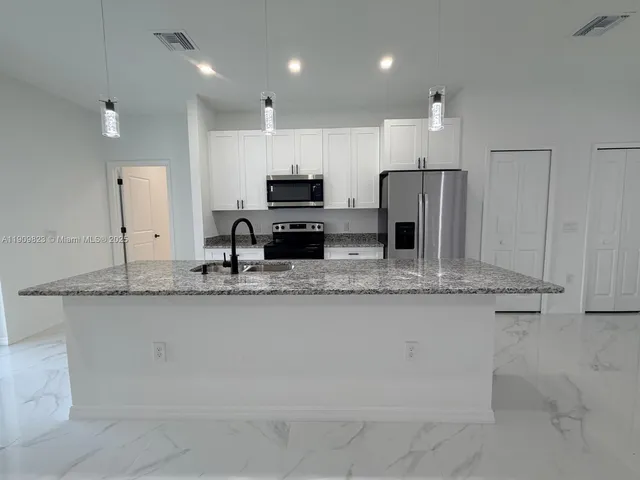 a large kitchen with granite countertop a sink and a refrigerator
