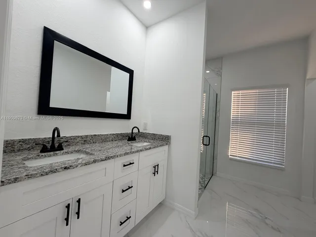 a bathroom with a granite countertop shower and a sink