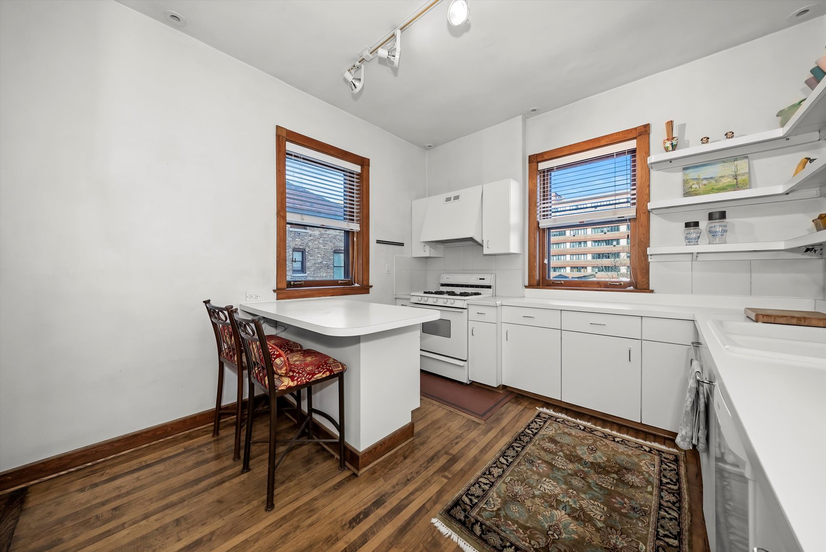 666 West Irving Park Road, Unit I4 Chicago, IL 60613 - Photo 18 of 27 a kitchen with stainless steel appliances kitchen island wooden floors and white walls