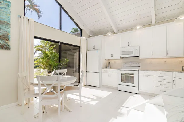 a kitchen with a stove a white refrigerator a dining table and chairs with wooden floor