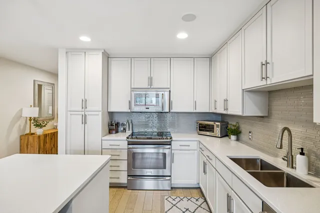 a kitchen with kitchen island white cabinets and stainless steel appliances