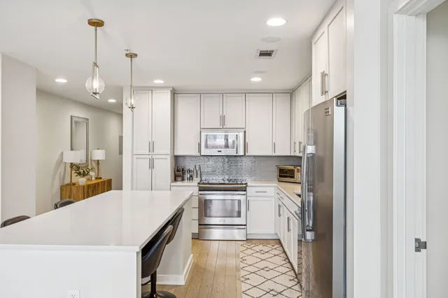 a kitchen with kitchen island a counter top space a sink stainless steel appliances and cabinets