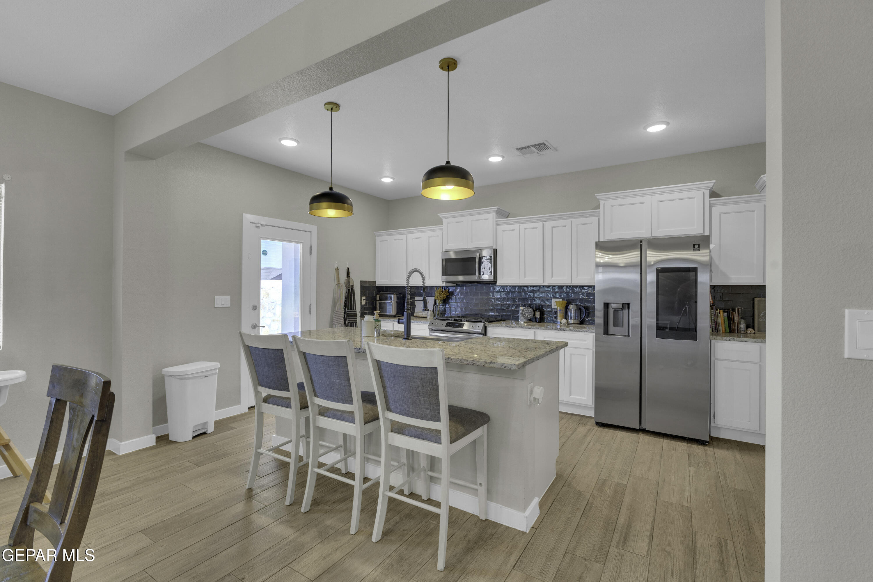 3529 Essence Street El Paso, TX 79938 - Photo 6 of 23 a kitchen with stainless steel appliances kitchen island granite countertop a table chairs and a refrigerator