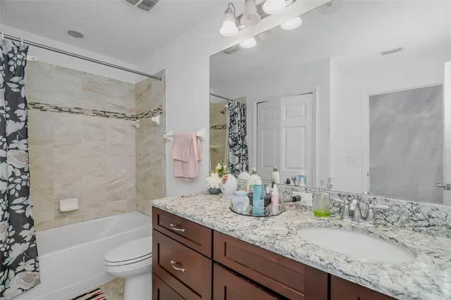 a bathroom with a granite countertop sink a toilet a mirror a shower and bathtub
