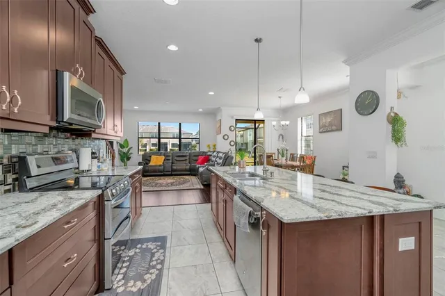 a kitchen with stainless steel appliances granite countertop a sink a stove and a wooden floors