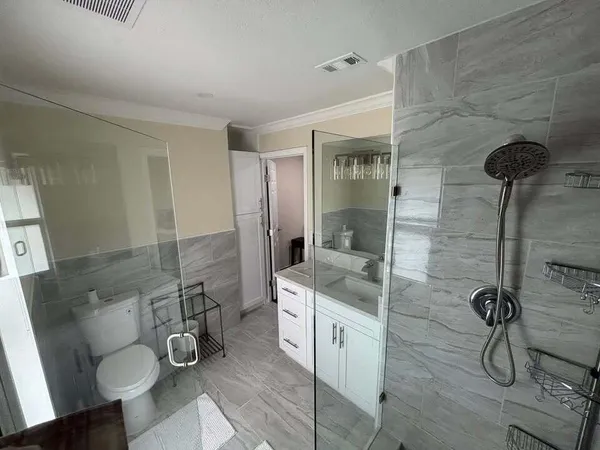 a bathroom with a granite countertop sink a toilet and shower