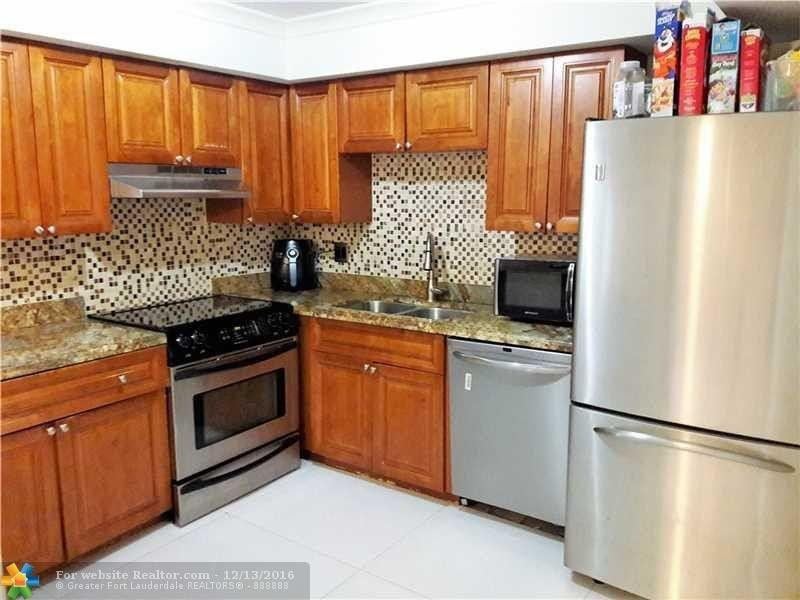 3316 Quail Close, Unit 21 Pompano Beach, FL 33064 - Photo 2 of 13 a kitchen with stainless steel appliances granite countertop a refrigerator sink and cabinets