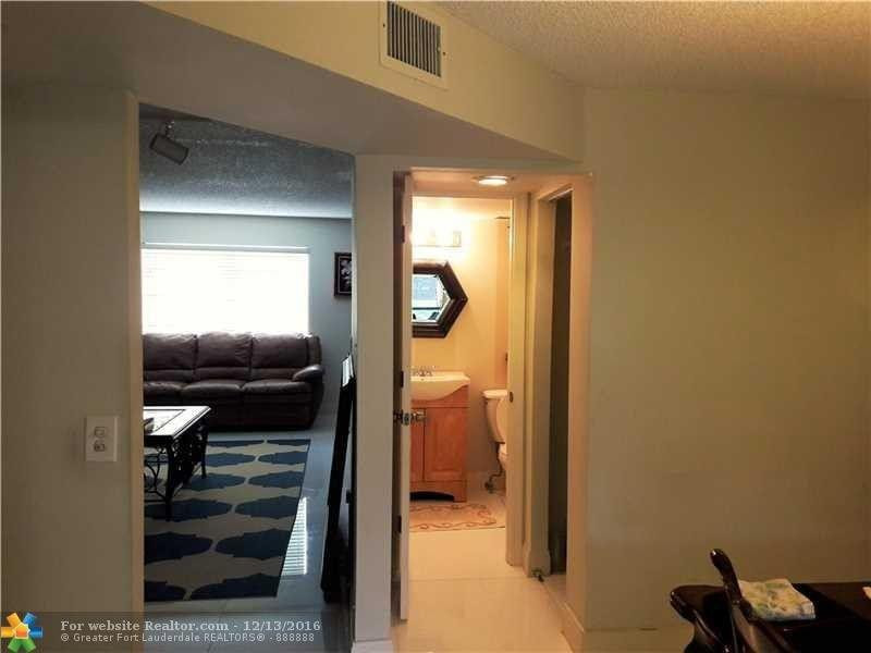 3316 Quail Close, Unit 21 Pompano Beach, FL 33064 - Photo 7 of 13 a hallway with a couch and a dining table next to a window