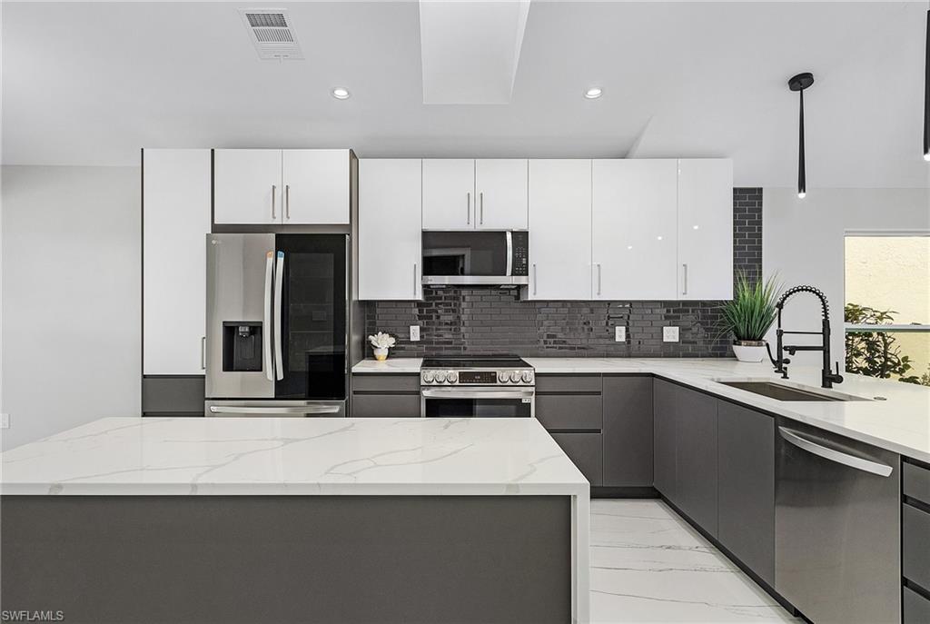 1601 Weybridge Circle, Unit 11 Naples, FL 34110 - Photo 2 of 34 a kitchen with a sink stainless steel appliances and white cabinets