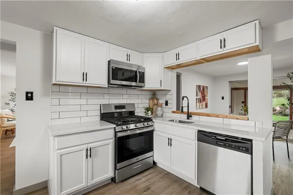 a kitchen with cabinets stainless steel appliances and wooden floor