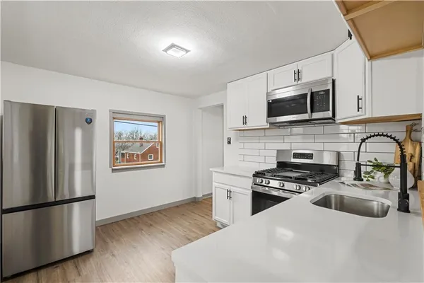 a kitchen with stainless steel appliances a stove sink microwave and refrigerator