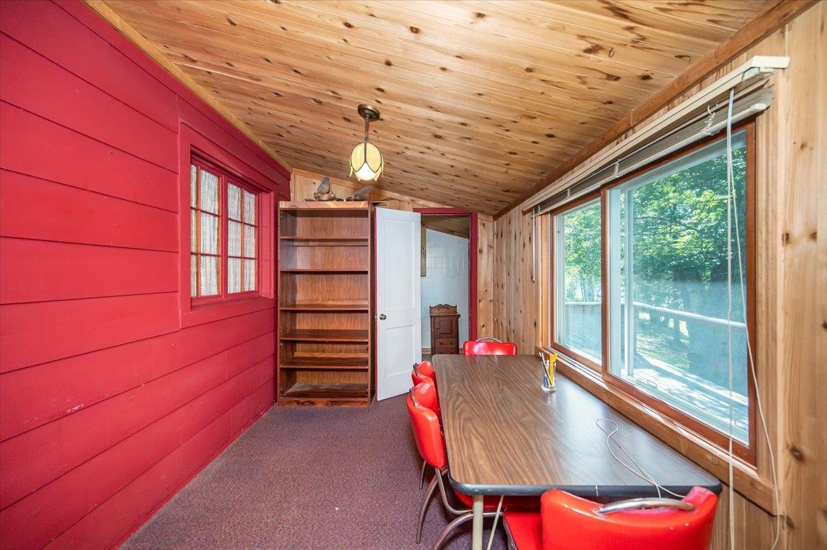 8977 Austin Road Alborn, MN 55702 - Photo 7 of 35 Dining room featuring lofted ceiling, wooden walls, dark carpet, a desk, and wooden ceiling