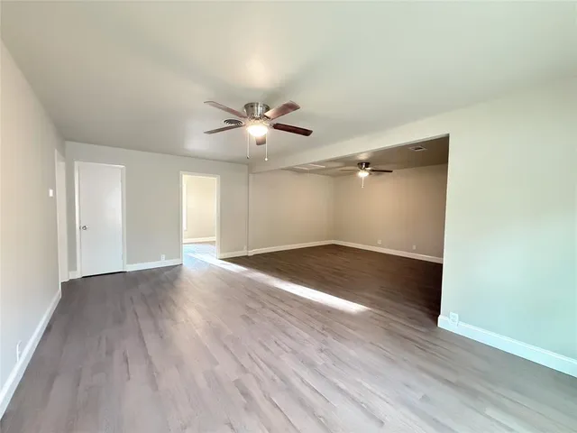 an empty room with wooden floor and ceiling fan