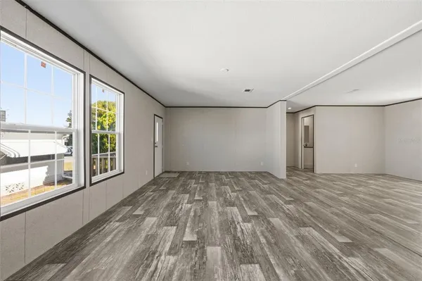 a view of an empty room with a window and wooden floor