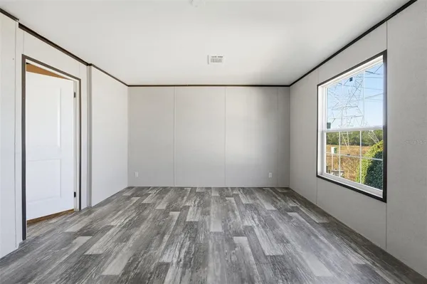 an empty room with wooden floor and windows