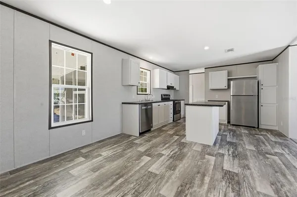 a view of a kitchen with a sink refrigerator and wooden floor