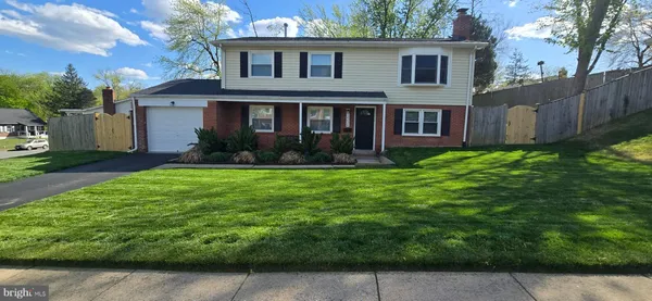a view of a yard in front of a house with plants and large tree