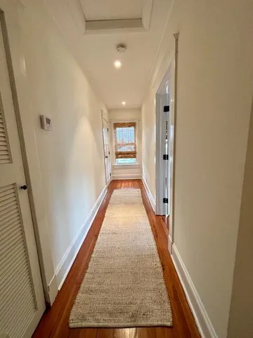 a view of a hallway with wooden floor and staircase