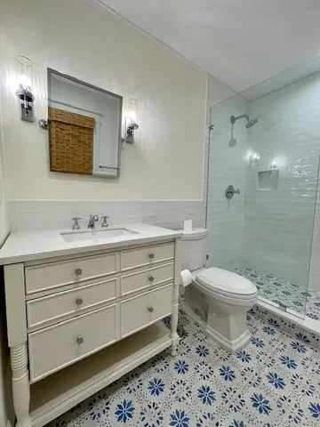 a bathroom with a toilet a sink a mirror a shower a vanity and window