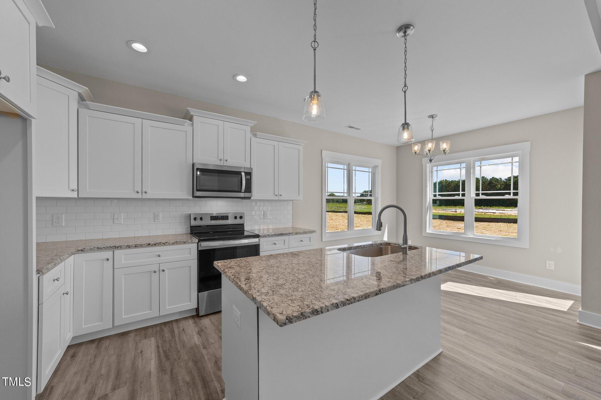 282 Fields Road Pikeville, NC 27863 - Photo 10 of 40 a kitchen with stainless steel appliances granite countertop a sink a stove and white cabinets with wooden floor