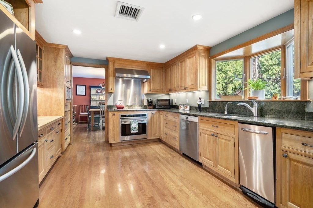 14 Independence Drive Brookline, MA 02467 - Photo 8 of 35 a kitchen with stainless steel appliances granite countertop a refrigerator a sink dishwasher a stove and white countertops with wooden floor