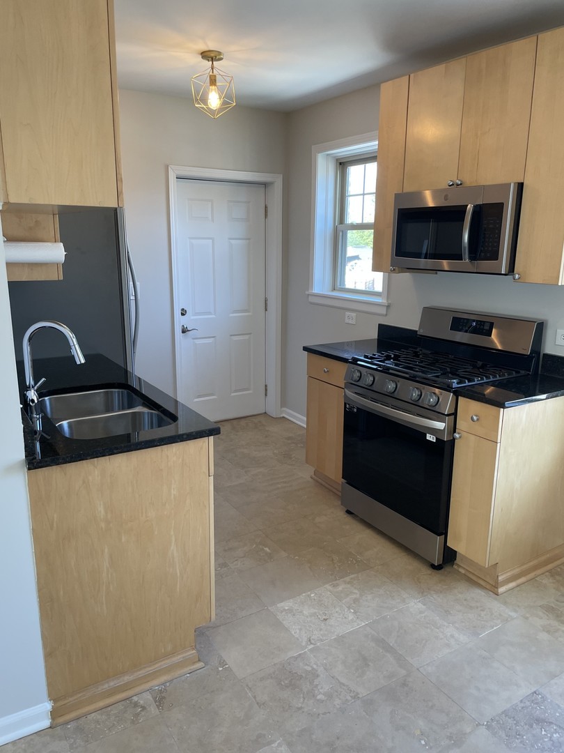 7318 North Honore Street, Unit 403 Chicago, IL 60626 - Photo 5 of 15 a kitchen with granite countertop a stove and a microwave