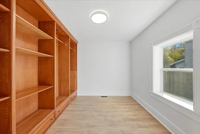 a view of an empty room with wooden floor and a window