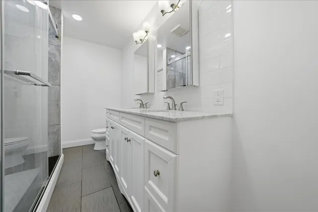 a bathroom with a double vanity sink toilet and shower