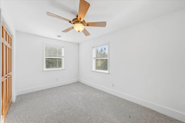 an empty room with windows and fan