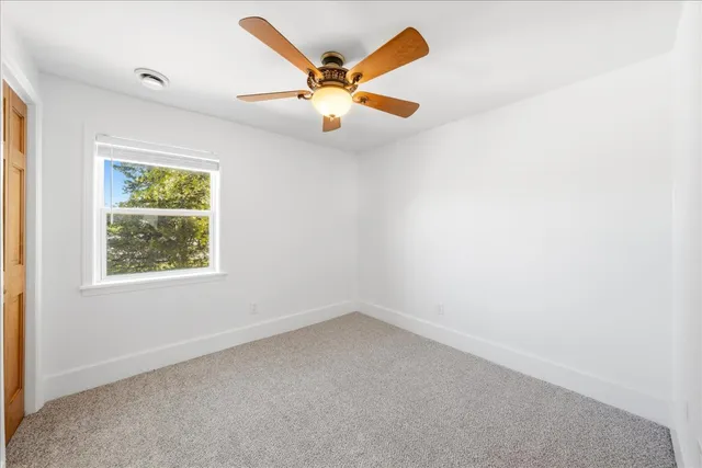 an empty room with window and ceiling fan