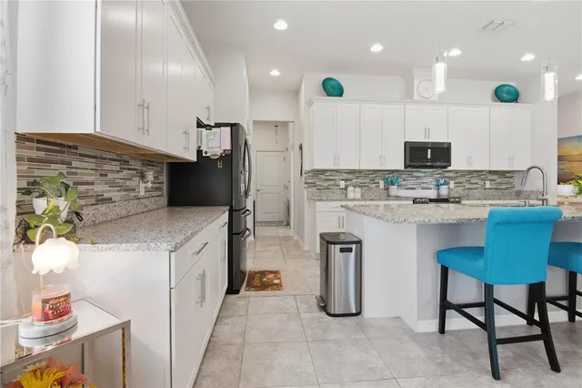 a kitchen with kitchen island granite countertop a sink and a refrigerator