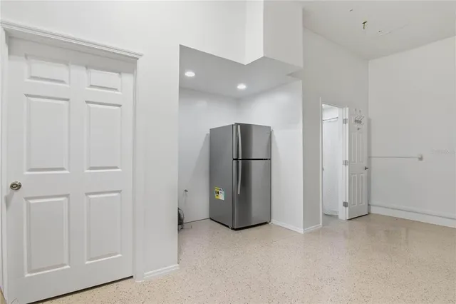 an empty room with a refrigerator and mirror