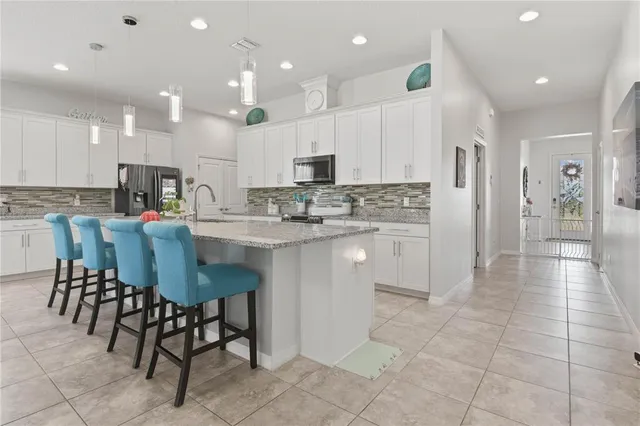 a kitchen with stainless steel appliances granite countertop a stove a sink a refrigerator and a dining table with wooden cabinets