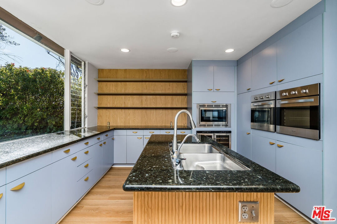 11271 Chalon Road Los Angeles, CA 90049 - Photo 16 of 35 a kitchen with kitchen island granite countertop a sink counter top space appliances and cabinets