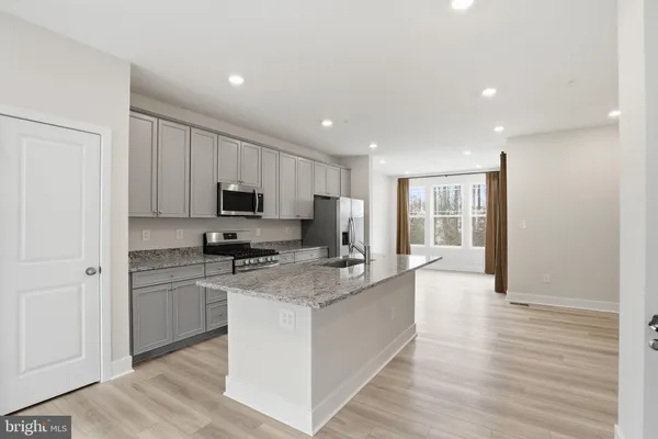 a large kitchen with granite countertop a stove top oven a sink dishwasher and a refrigerator with wooden floor