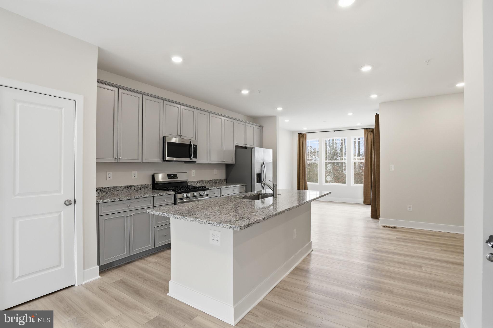 1810 Betterton Road Essex, MD 21221 - Photo 13 of 34 a large kitchen with granite countertop a stove top oven a sink dishwasher and a refrigerator with wooden floor